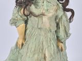 an image of a doll with long hair wearing a green dress and gloves