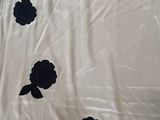 a white sheet with black flowers on it on a bed
