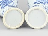 pair of blue and white vases with flowers on them on a gray surface