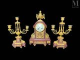 trois bougeoirs dorés et rouges et une horloge sur fond noir