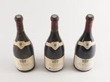 three bottles of wine sitting next to each other on a white surface