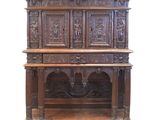une vieille armoire en bois ornée de sculptures, notamment sur le dessus