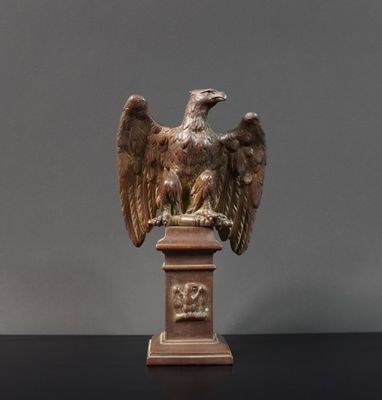 statue d'un aigle posée sur un socle, sur une surface noire