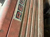 a rusted out old red truck with a sign on it
