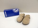 pair of tan sued clogs with a box on a white surface