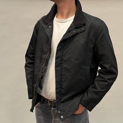 un homme debout, vêtu d'une veste noire et d'un jean