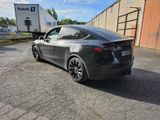 the tesla model 3 is parked in a parking lot with a trailer in the background