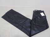 un gros plan sur un pantalon en cuir noir posé sur une surface blanche