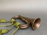a brass trumpet with a green cord on a gray surface