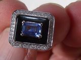 a person holding a ring with a blue stone in it