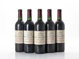 quatre bouteilles de vin rouge sont alignées sur une surface blanche