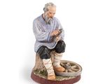 figurine représentant un vieil homme assis sur une souche d'arbre, tenant un panier de pain