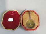 une petite boîte rouge contenant une horloge dorée