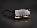 sac à main marron et blanc muni d'une chaîne, sur fond noir