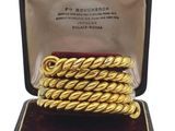 un gros plan sur une paire de bracelets en or tressé dans un écrin