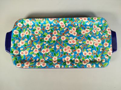 un plateau orné d'un motif floral bleu et blanc, muni d'une poignée bleue