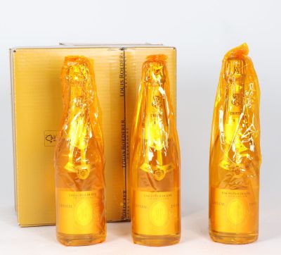 trois bouteilles contenant un liquide de couleur dorée posées à côté d'une boîte