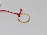 une bague en or à laquelle est attaché un cordon rouge
