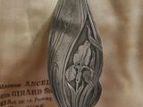 a silver spoon with a flower on it sitting on a table