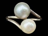 two white pearls are sitting on top of a silver ring