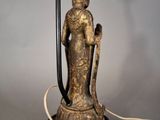 a statue of a woman holding a lamp on a table