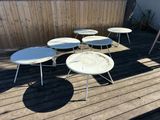 several white tables and chairs on a wooden deck in a backyard