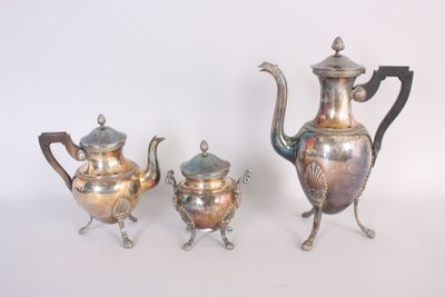 trois théières en argent et une théière posées sur une table