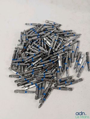 un tas de vis posées sur une table, sur fond blanc