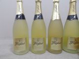 four bottles of sparkling wine are lined up on a table