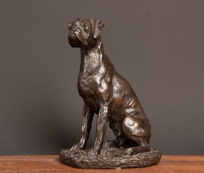a bronze statue of a dog sitting on top of a wooden table