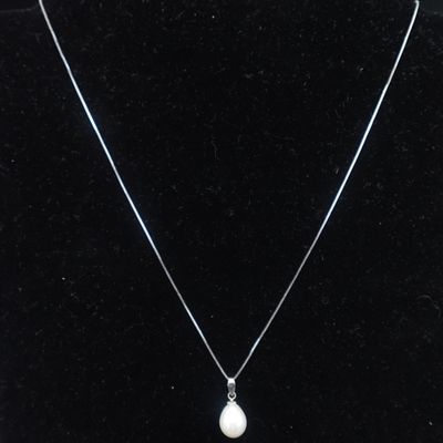 Un collier orné d'une perle blanche est accroché à un mannequin noir