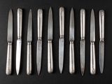 six knives are lined up in a row on a black surface