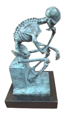 statue of a skeleton sitting on a block with a hammer in his hand