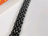 a close up of a black bracelet on a white surface