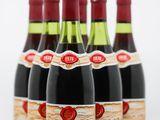 six bouteilles de vin sont alignées sur une surface blanche