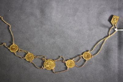 a close up of a gold coin necklace on a black surface