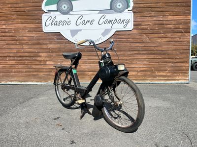 un vélo garé devant un immeuble où est accrochée une pancarte
