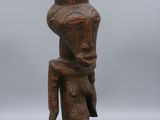 une petite statue en bois représentant un homme à la grosse tête