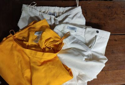 three pairs of yellow and white pants sitting on top of a wooden bench