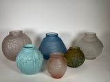 five different colored vases sitting on a white surface