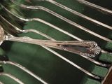 many spoons and forks on a green cloth