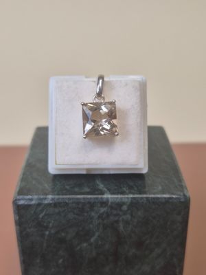 a small square pendant with a diamond on top of a marble block