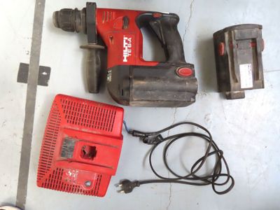 une perceuse filaire et deux batteries posées par terre