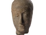 statue représentant une tête de Bouddha posée sur un socle, sur fond blanc