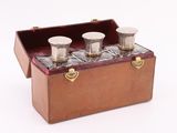 four shot glasses in a wooden case on a white background