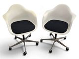 pair of white chairs with black cushions and wheels on a white surface