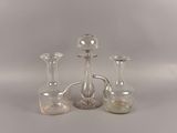 three glass vases and a decanter sitting on a table