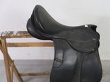 un gros plan d'une selle noire posée sur un banc en bois