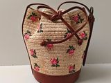 straw bag with pink flowers on it sitting on a white surface