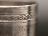 close up of a silver cup on a table with a black background